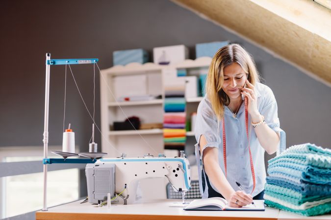 Cheerful seamstress talking on smartphone