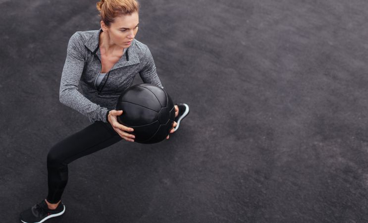 Sportswoman stretching outdoors with medicine ball