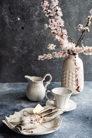 Top view of spring floral concept with apricot blossom in modern vase on grey room with tea cups
