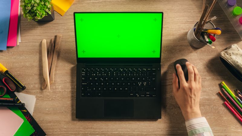 Anonymous Designer Typing on a Laptop with Mock-Up Green Screen Chromakey Display with Motion Tracker Placeholders. Illustrator Using a Computer, Working on a Digital Art Portfolio. Top Down View