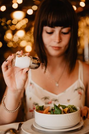 Woman salting salad in restaurant