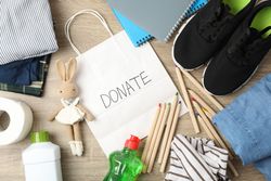 Text Donate, clothes and different accessories on wooden background, top view