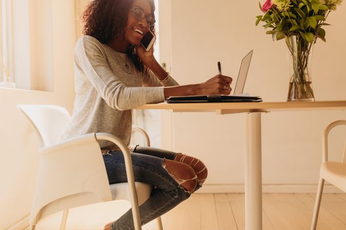 Woman entrepreneur taking notes while working remotely