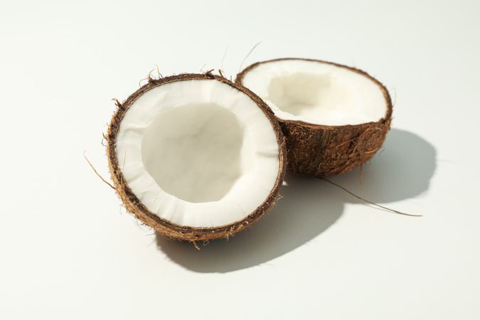Halves of coconut on plain background, close up