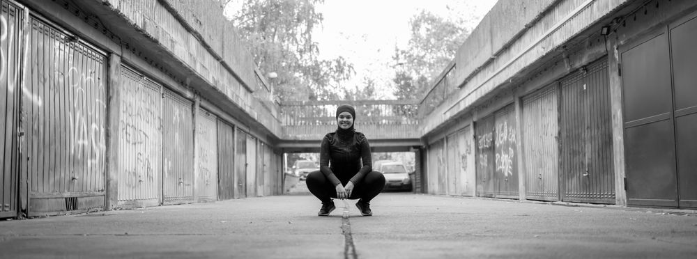 Smiling woman crouching down, centered on a quiet lane