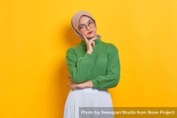 Woman in headscarf and glasses looking up with hand on chin 5neXZ0