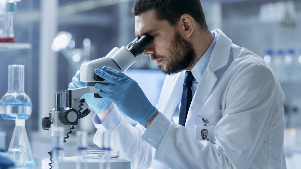 Research Scientist Looks into Microscope.