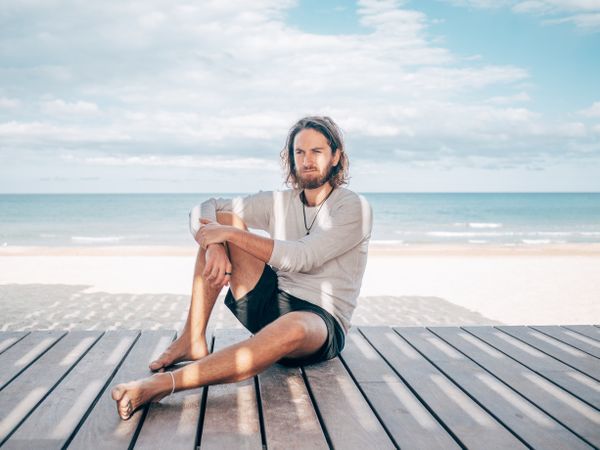 Man sitting on wooden pier on the beach