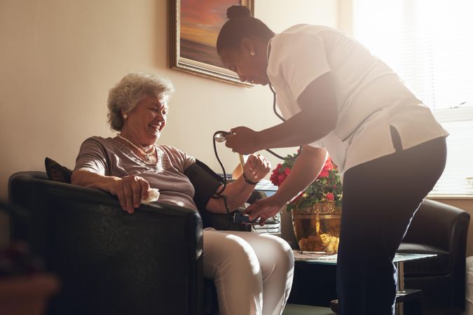 Home caregiver doing routine checkup of a mature female patient