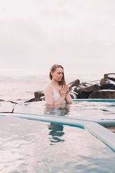Woman sitting in pool near stones
