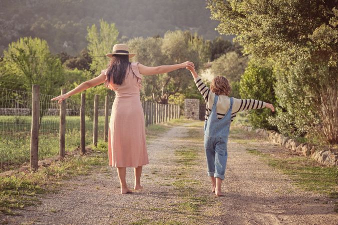 Woman with son holding hands walking in park