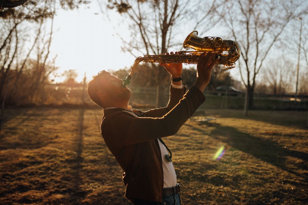 young musician playing the saxophone at sunset