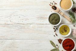 Top view of wooden scoop full of peppercorn with bowls of spice, copy space