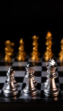 Silver chess pieces against golden rivals