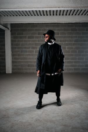 Male in stylish wear standing near dark walls
