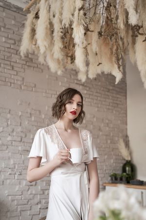 Pensive woman looking away and contemplating while having hot drink in kitchen
