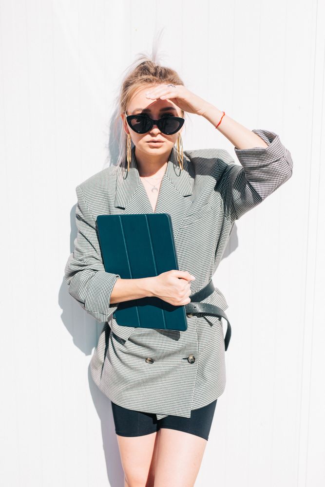 Stylish businesswoman with laptop leaning on wall