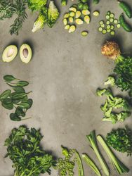 Arrangement of sliced green garden vegetables on concrete surface, copy space, vertical composition