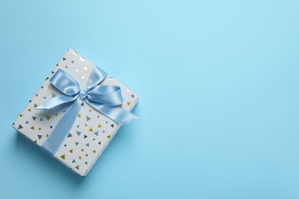 Gift box with bow on blue background, space for text
