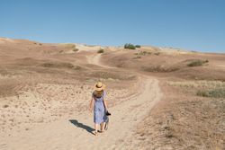 Young female photographer walking on dry field