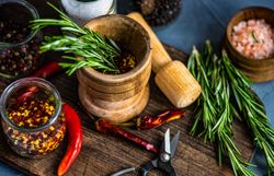 Rosemary in wooden mortar on kitchen counter with other seasonings 