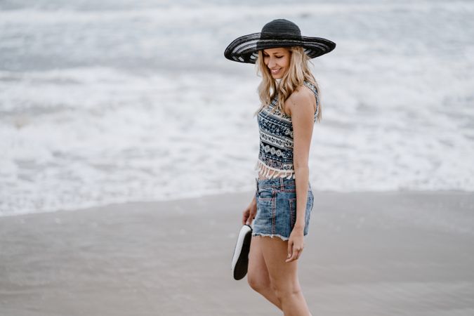 Young female walking barefoot on sandy beach