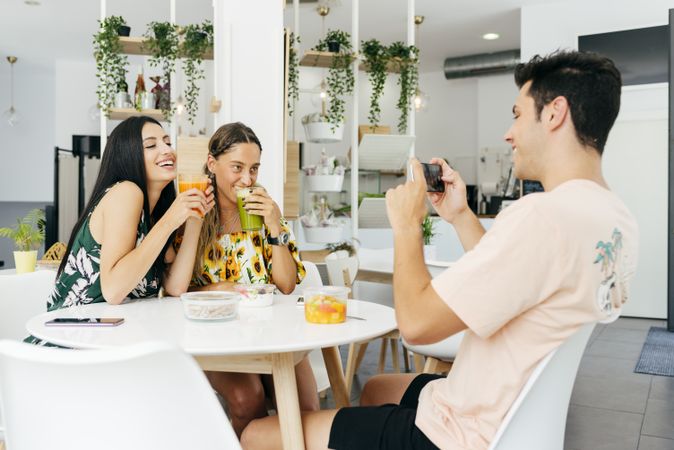 Man taking picture of friends in cafe