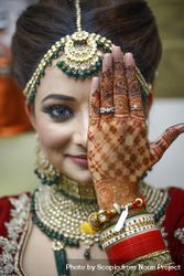 Indian bride covering her eye with henna hand 5QkaGb