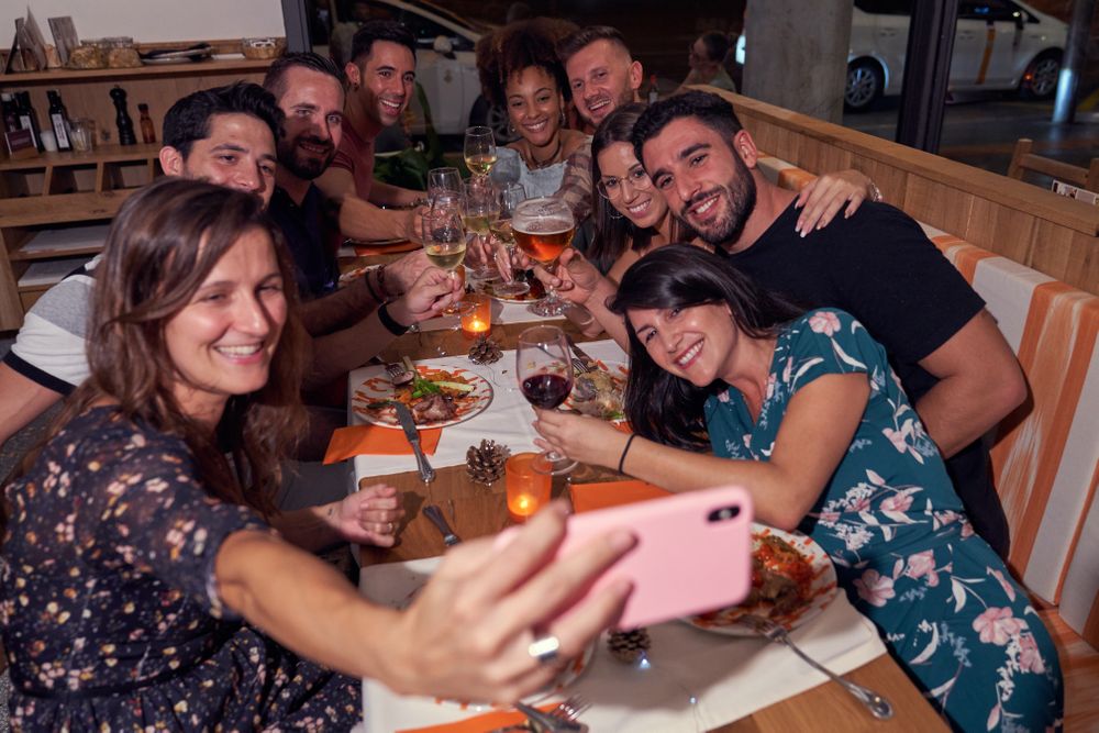 Cheerful diverse friends taking selfie in restaurant
