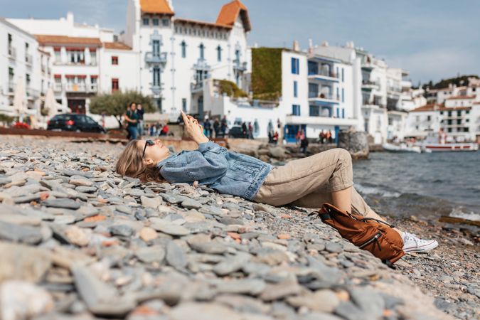 Woman lying on the ground while using a smartphone on sunny day