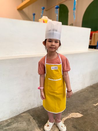 A little girl wearing a chef's hat and apron was in the kitchen