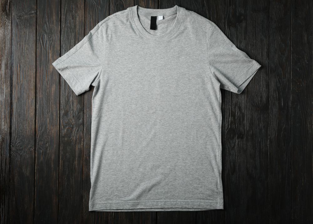Blank gray t-shirt on wooden background, space for text