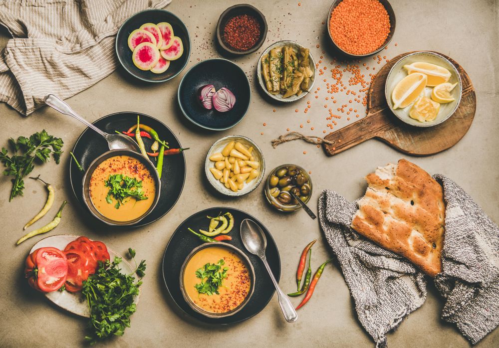 Spread of yellow lentil soup bowls, with bread, and vegetable garnishes