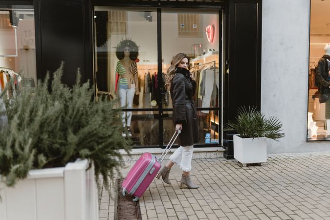 Woman with suitcase walking on street