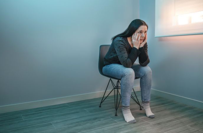 Pensive woman with lost look sitting on a chair