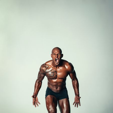 Muscular man screaming against grey background
