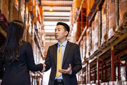Asian professional male shaking hands of female colleague
