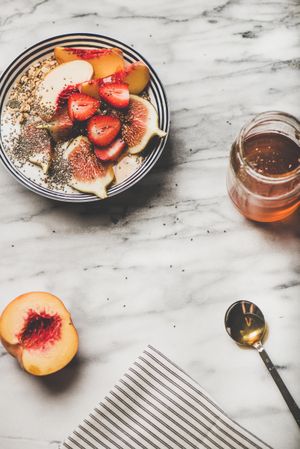 Flat-lay of yogurt bowl with fruit, honey and spoon