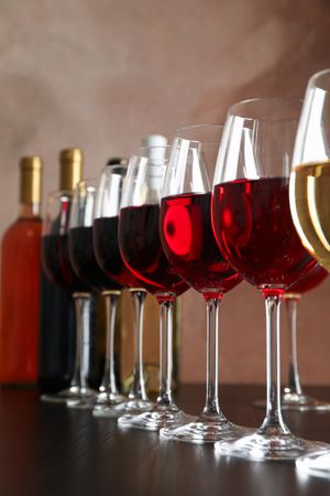 Bottles and glasses with wine on dark table, close up
