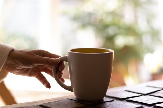 Hand of a mature woman holding a cup of coffee.