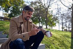 Cheerful mature man surfing smartphone in park