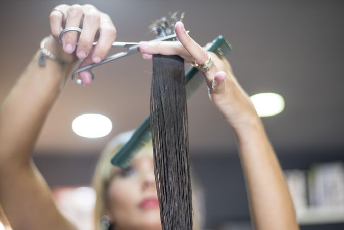 Hair stylist holding up brunette wet hair and trimming ends