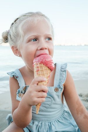 Blond girl eating ice cream on summer seashore