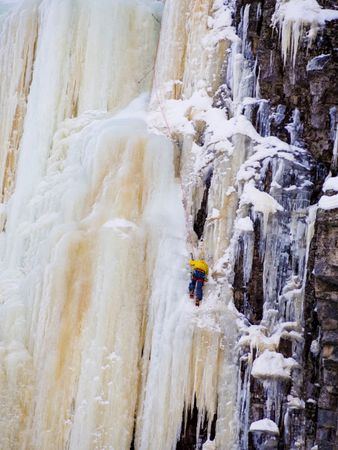 Person in yellow scaling icy wall