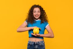 Girl holding piggy bank, emphasizing importance of saving