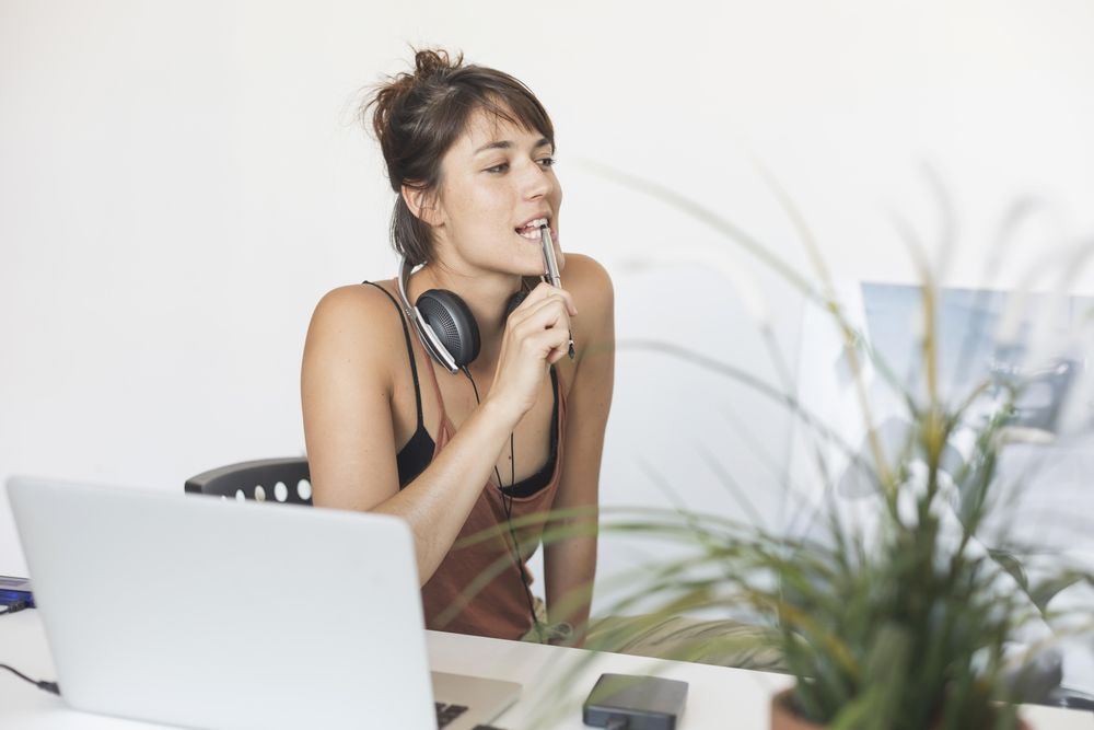 Woman thinking at desk with pen to her mouth