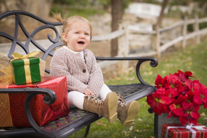 Young Toddler Child Sitting on Bench with Christmas Gifts Outside