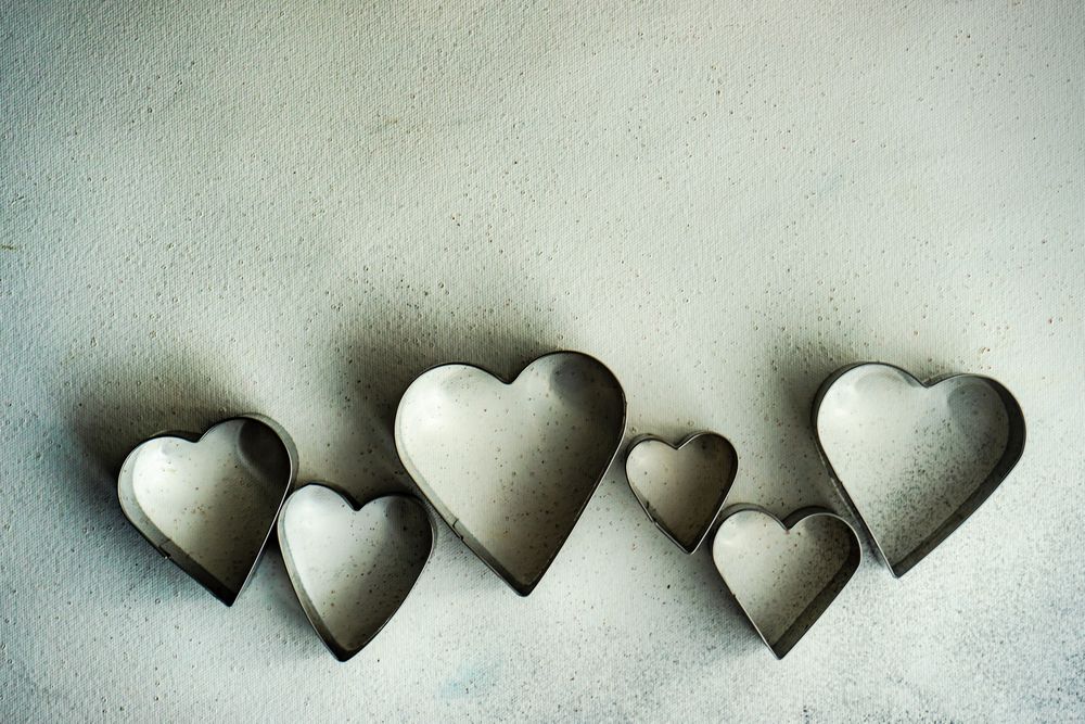 Top view of heart shaped cookie cutters scattered on grey counter