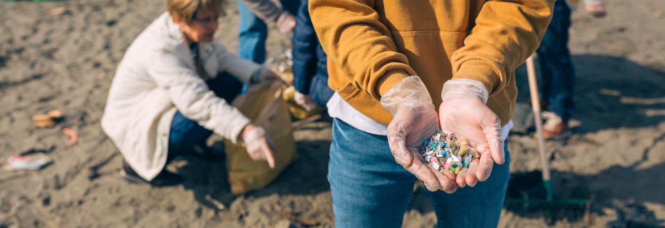 Hands with microplastics on the beach