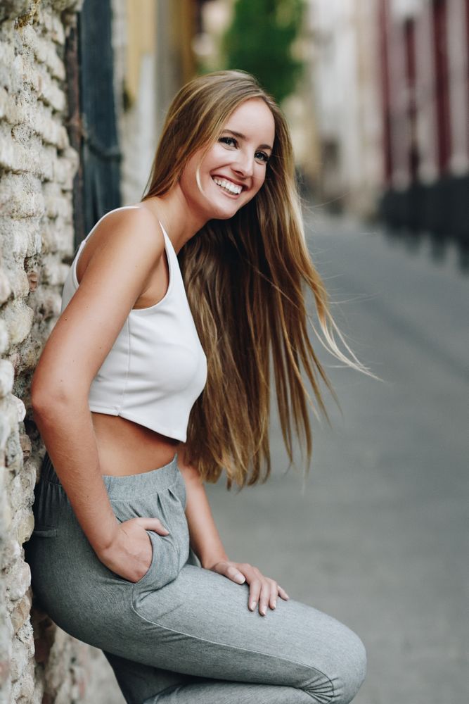 Side view of long haired chic woman leaning on wall outside